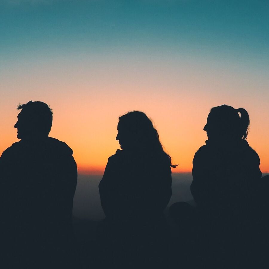 Freunde genießen das Abendrot am Gipfel der Berge.